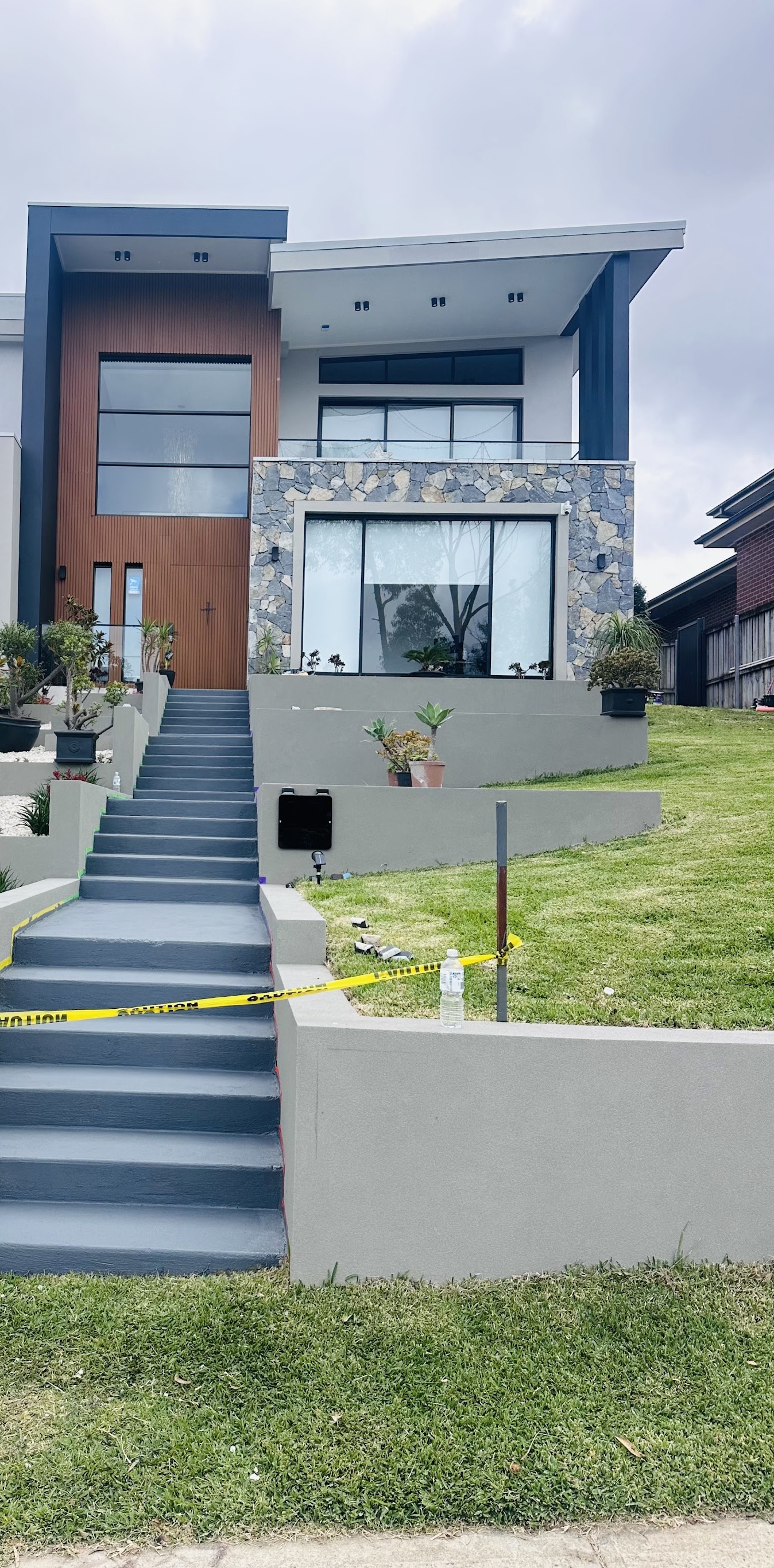 Wide grey front steps rising through a terraced front garden to a modern house