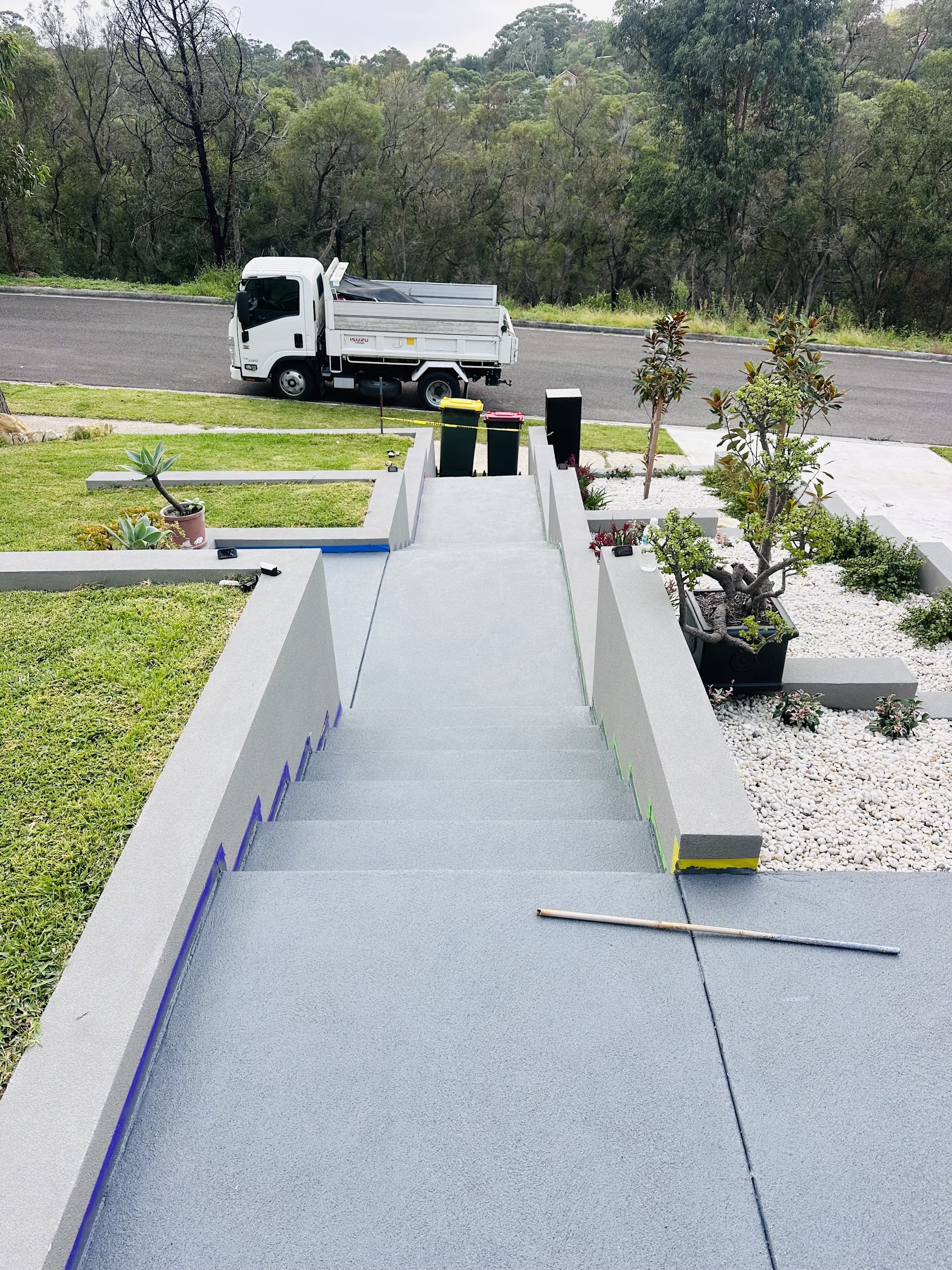 Rendered front stairway with low walls and white pebble garden beds, work truck parked on the street